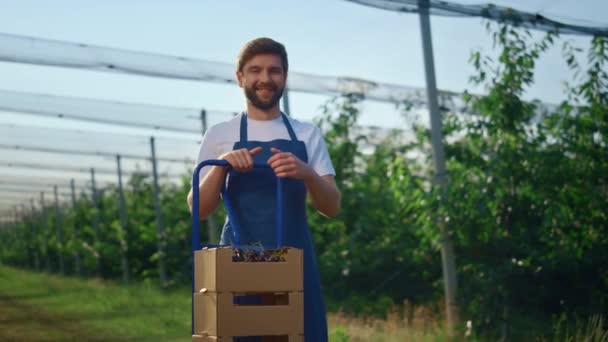 Hombre agrónomo mirando cámara en huerto de frutas. Agricultor mostrar cosecha en el jardín. — Vídeo de stock