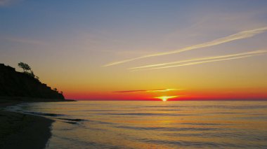 Dağ silueti olan sakin bir okyanus kıyısı. Deniz ufku ufuk çizgisi