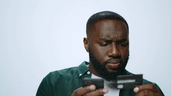 Retrato de hombre africano serio de compras en línea en el teléfono inteligente en el estudio —  Fotos de Stock