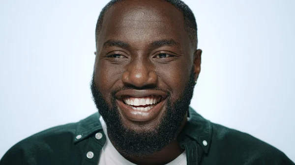 Portret van een lachende Afrikaan die lacht naar de camera op een lichte achtergrond — Stockfoto