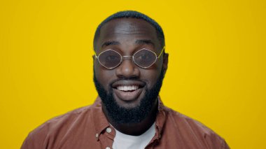 Yakın plan Afro-Amerikalı adam sarı arka planda evet diyor..