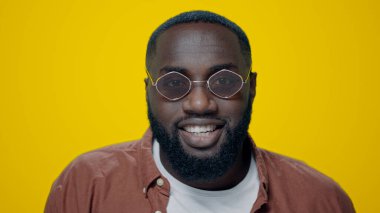 Mutlu Afro-Amerikalı bir adamın portresi sarı arka planda evet işareti gösteriyor.,