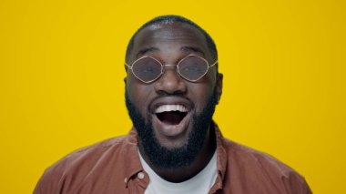 Sarı arka planda poz veren şaşırmış Afrikalı Amerikalı adamın portresi.. 