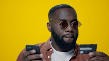 Stüdyoda online ödeme için kredi kartı kullanan yakın plan sakallı afro adam..