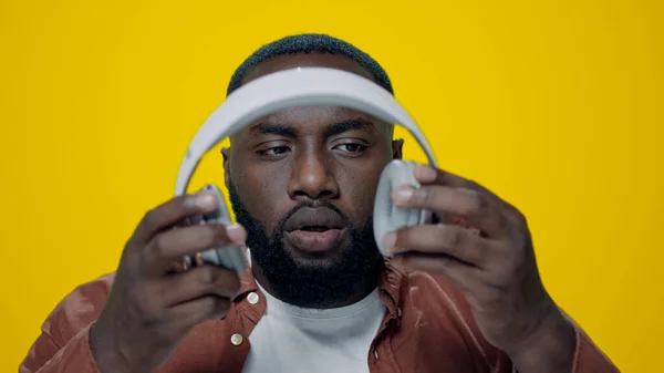 Πορτρέτο του έκπληκτος αφρικανός τύπος ακούγοντας μουσική στα ακουστικά στο στούντιο. — Φωτογραφία Αρχείου