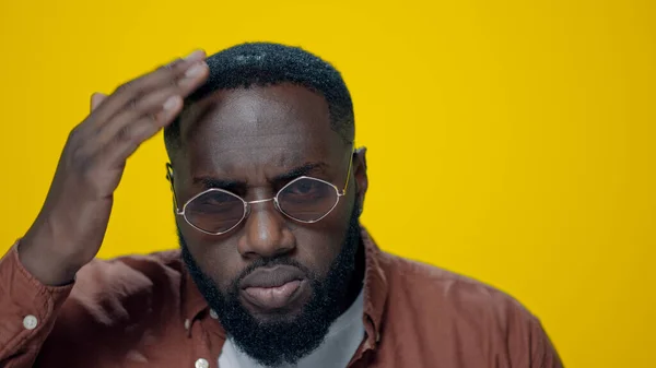 Retrato de un hombre afroamericano serio comprobando la barba sobre fondo amarillo. —  Fotos de Stock