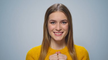 Yakından, elleri gri arkaplanda dudaklarına dokunan çekici bir kadın.. 