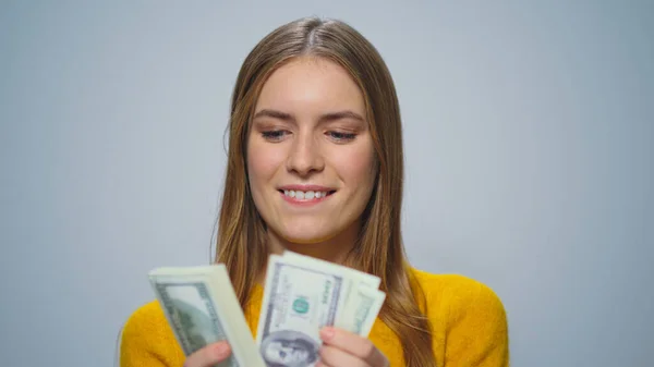 Portrét mladé usměvavé ženy počítání peněz na šedém pozadí ve studiu. — Stock fotografie