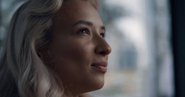 Bulanık arka planda sarı saçlı, beyaz bir kadın yüzü var..