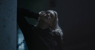 Sarışın kız, gece poz veriyor. Kapüşonlu, şehir arka planında.. 