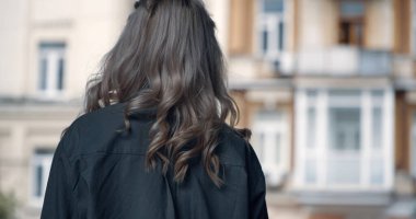 Sarışın kız modern mimarinin yanında şehir manzarasında yürüyor..