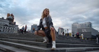 Şehir merkezindeki akşam caddesinde kendine güvenen bir kadın poz veriyor..