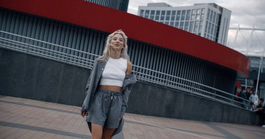 Şehir merkezindeki modern kentsel binaların yakınında yürüyen seksi kadın..