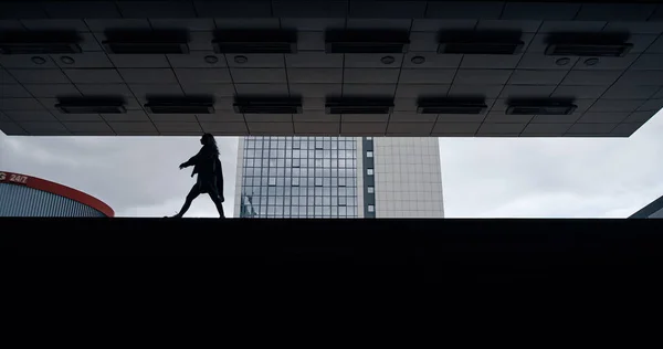 Silhouette femme marche parking bâtiment sombre en ville en plein air. — Photo