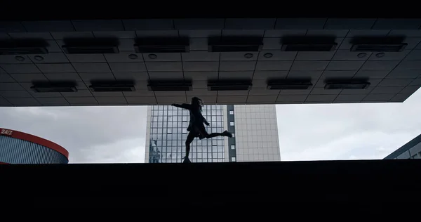 Silhouette femme sautant dans la station souterraine sombre ou un parking. — Photo