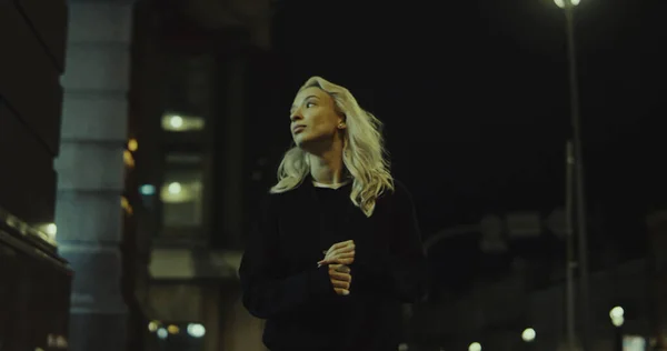 현대 도시의 조명을 입고 도시에서 혼자 걷는 금발 여자. — 스톡 사진