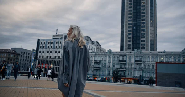 도시 광장을 걷고 있는 여자가 저녁에는 도시 건물 들 과 함께 걸어 다닌다. — 스톡 사진
