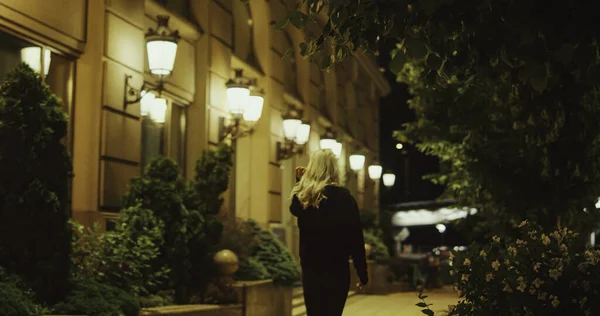 Kobieta wyjeżdża na ulicę późno w nocy w nowoczesnym mieście na zewnątrz. — Zdjęcie stockowe