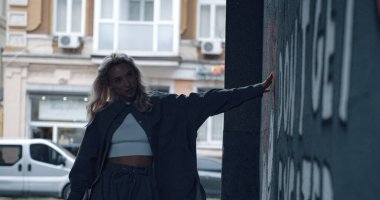 Modern şehir arka planında duvar yazısı arayan bir kız. 