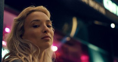 Sarışın manken yüzü gece şehrinin neon ışıklarındaki kameraya benziyor.. 