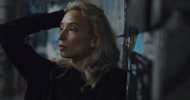 Şehir kadını kameraya poz veriyor. Gece caddelerinde sarı saçlara dokunuyor.. 