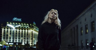 Kentin arka planında, gece sokak lambalarında yürüyen kendinden emin bir kız.. 