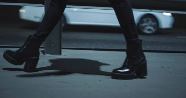 Woman legs walking highway at late night dark road with passing cars.