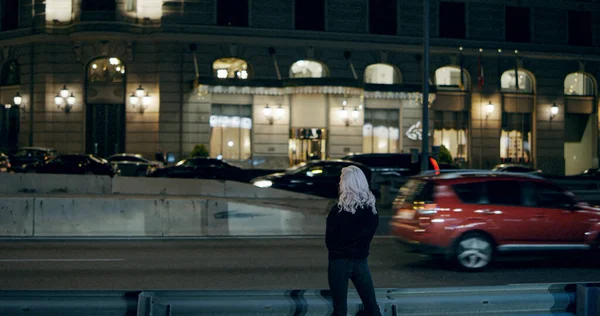 Женщина, стоящая ночью на шоссе в городской одежде в центре города. — стоковое фото