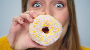 Yakından gülümseyen kadın gri arka planda donutlarla eğleniyor.. 