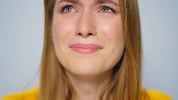 Closeup attractive woman crying at camera on grey background in studio.