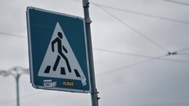 Şehrin arka planında bulut havasında yaya geçidi tabelası. 