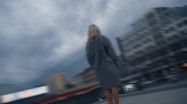 Sarışın kadın, şehir merkezinde yağmurlu bir şehirde ayakta duruyor.. 