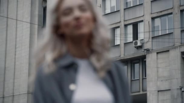 Блондинка усміхнений міський пейзаж біля будівель на розмитому фоні — стокове відео