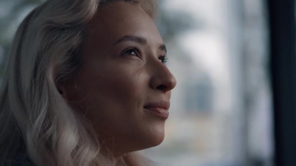 Caucasiano rosto feminino olhando para longe com o cabelo loiro na cidade de fundo borrada. — Vídeo de Stock