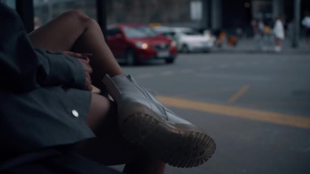 Weibliche Beine Bushaltestelle in der Stadt Hintergrund. Mädchen wartet auf Fahrt im Stadtgebiet. — Stockvideo