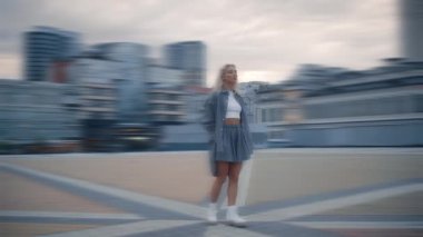 Modern binaların, sokak lambalarının yanında akşam modelliği yapan kadın..