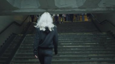 Şehirde merdivenlere çıkan genç bir kadın. Sokakta giyinmiş..