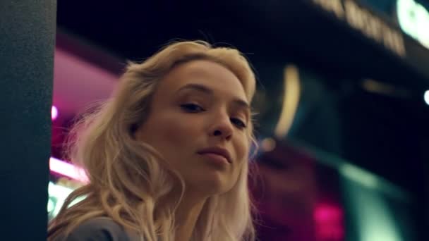 Blondynka model twarz patrząc aparat w neonowe światła w mieście nocy. — Wideo stockowe