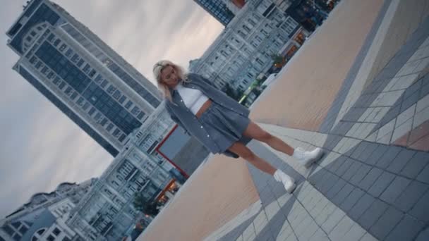 Blondýny model pózování město ve večerních hodinách na náměstí moderní budovy. — Stock video