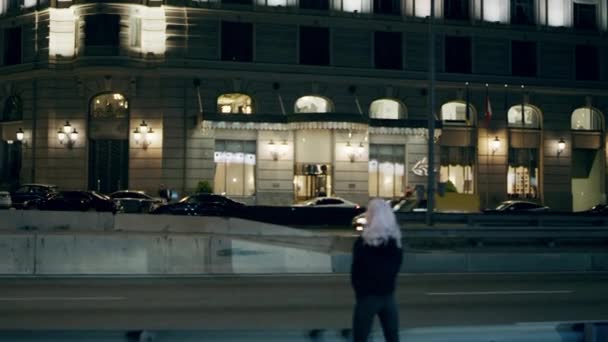 Γυναίκα στέκεται νύχτα αυτοκινητόδρομο φορώντας αστική φθορά στο κέντρο της πόλης. — Αρχείο Βίντεο