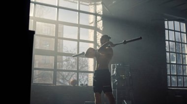 Vücut geliştirici halterle çömelme hareketi yapıyor. Beden eğitimi alan bir adam.