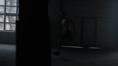 Erkek koşucu başlangıç pozisyonunda duruyor. Spor salonunda koşan üstsüz bir adam.