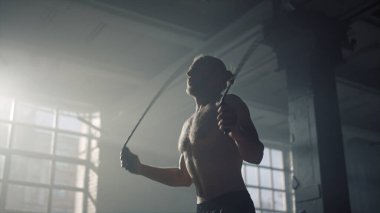 Atlayan bir atlet ip atlıyor. Çıplak gövdeli kaslı bir adam atlama ipi kullanıyor. 