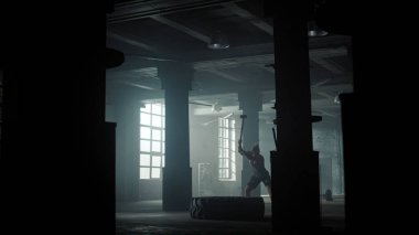 Çatı katında erkek eğitimi. Aktif sporcu çekiçle lastik lastiğe vuruyor.