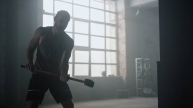 Kızgın adam çekiçle lastiğe çarpıyor. Adam fiziksel egzersiz yapıyor.