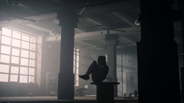 Tahta kutunun üzerinde diz çöküp mekik çeken bir kız. Vücut geliştirici karın kaslarını çalıştırıyor