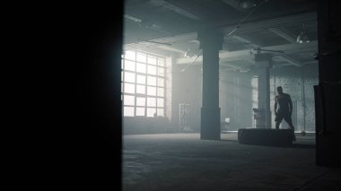 Spor adam ağır lastik lastiği kaldırıyor. Sporcu yoğun antrenman yapıyor. 