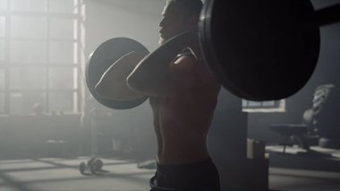 Adam ağırlık kaldırıyor. Erkek vücut geliştirici halterle çapraz uyum çalışması yapıyor.