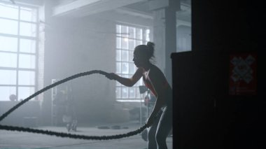 Vücut geliştirici beden eğitiminde halat egzersizi yapıyor. Spor kulübünde kız eğitimi