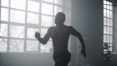 Spor salonunda kardiyo çalışması yapan bir sporcu. Çatı katında koşan sporcu